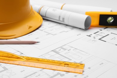 Pencil, ruler and hardhat on blueprints, closeup
