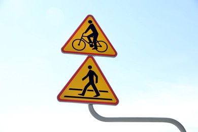 Signpost with cycle route and pedestrian crossing ahead against blue sky