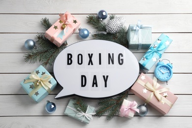 Flat lay composition with Boxing Day sign and Christmas gifts on white wooden table