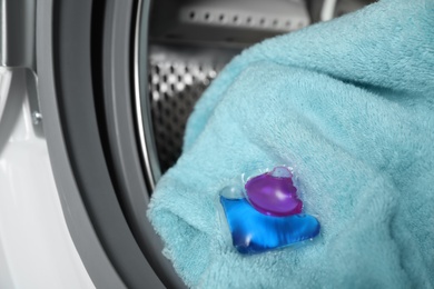 Laundry detergent capsule and towel in washing machine drum, closeup view