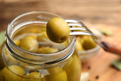 Glass jar of pickled olives and fork, closeup