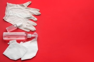 Flat lay composition with medical gloves, masks and hand sanitizers on red background. Space for text