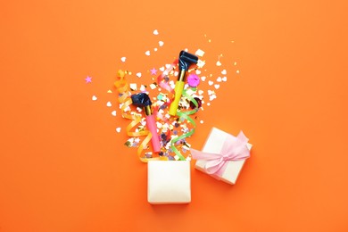 Beautiful flat lay composition with gift box and festive items on orange background. Surprise party concept