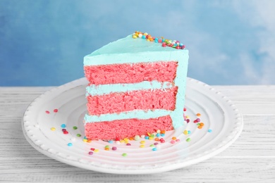 Slice of fresh delicious birthday cake on table against color background