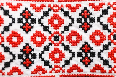 Beautiful red Ukrainian national embroidery on white fabric, top view