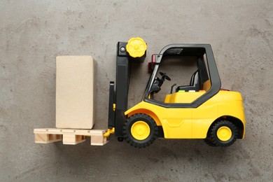 Toy forklift with wooden pallet and box on light grey table, top view