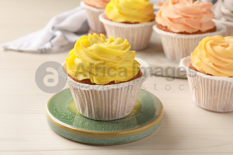 Photo of Tasty colorful cupcakes on white wooden table