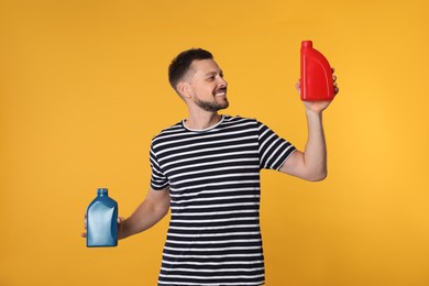 Man holding two containers of motor oil on orange background