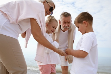 Cute little children with grandparents on sea beach