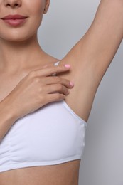 Young woman showing smooth skin after epilation on white background, closeup