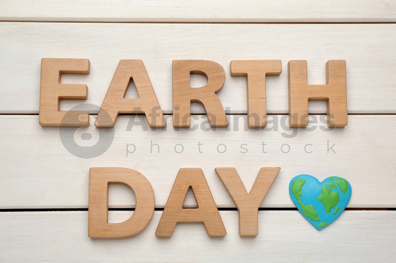 Words Earth Day and heart shaped plasticine planet on white wooden table, flat lay