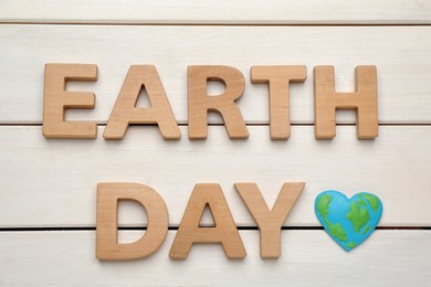 Words Earth Day and heart shaped plasticine planet on white wooden table, flat lay