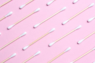 Many cotton buds on pink background, flat lay