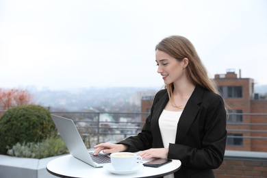 Businesswoman working with laptop in outdoor cafe. Corporate blog