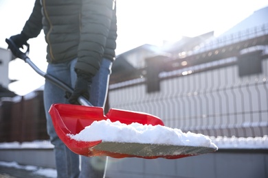 Photo of Person shoveling snow outdoors on winter day, closeup