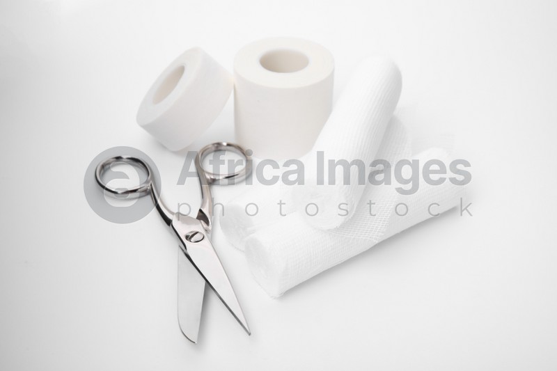 Photo of Medical bandage rolls, sticking plaster and scissors on white background