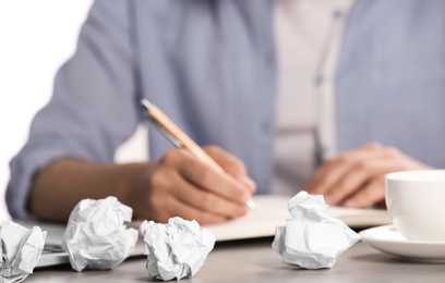 Woman working at table with crumpled paper, closeup. Generating idea