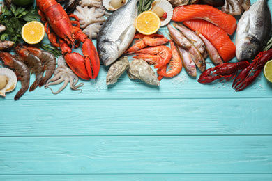Fresh fish and different seafood on blue wooden table, flat lay. Space for text