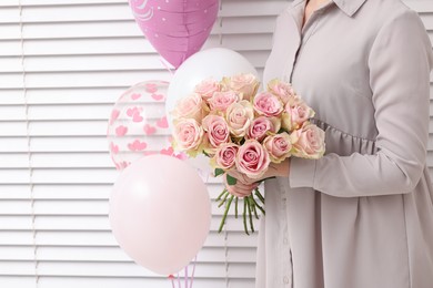 Photo of Woman holding bouquet of beautiful rose flowers near air balloons indoors, closeup view and space for text. Happy birthday