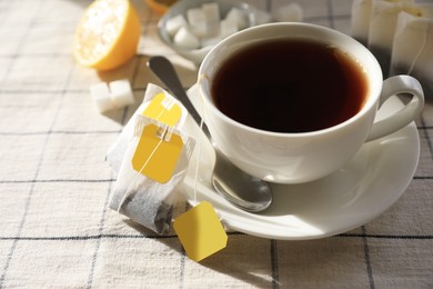 Tea bags near cup of hot drink on table, closeup