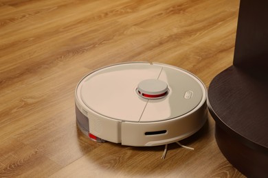Robotic vacuum cleaner on wooden floor indoors