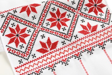 Traditional Ukrainian embroidery on white canvas as background, closeup. National handicraft