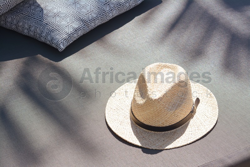 Photo of Stylish straw hat and pillows on grey fabric outdoors, space for text