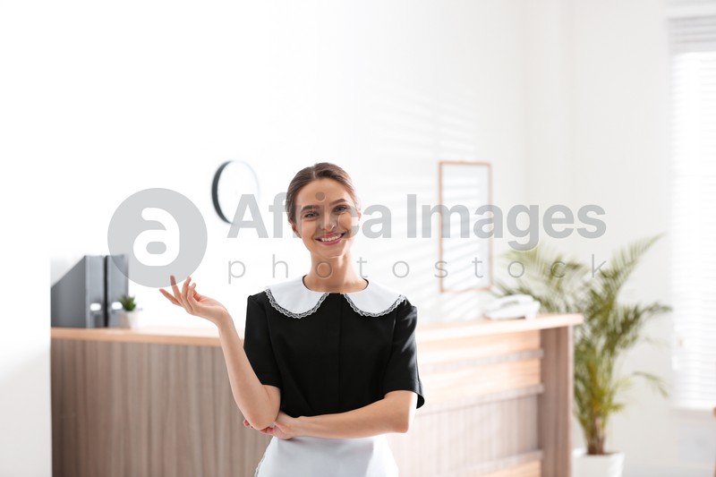 Photo of Portrait of young chambermaid near reception in hotel