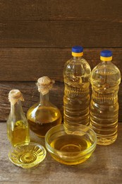 Photo of Bottles and bowls with sunflower oil on wooden table