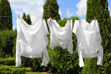 Photo of Clean clothes hanging on washing line in garden. Drying laundry