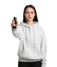 Young woman using pepper spray on white background