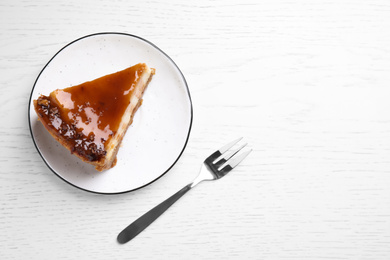 Piece of delicious cake with caramel on white wooden table, flat lay. Space for text