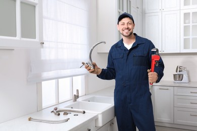 Photo of Professional plumber with water tap and wrench in kitchen
