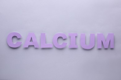Photo of Word Calcium made of purple letters on light grey background, flat lay