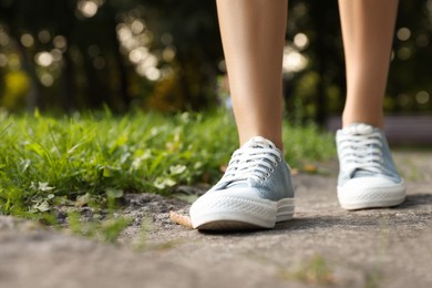 Photo of Woman in stylish shoes walking near green grass outdoors, closeup
