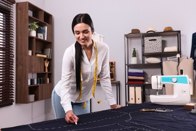 Photo of Dressmaker marking fabric with chalk in workshop