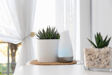 Photo of Plant and oil diffuser on table indoors. Home design idea