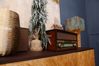 Photo of Retro radio and small decorative Christmas tree on cabinet in room