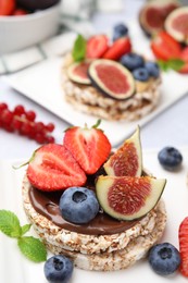 Tasty crispbreads with chocolate, figs and berries served on light table, closeup