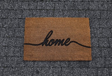 Photo of Doormat with word Home on pavement, top view