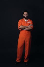 Happy prisoner in jumpsuit on black background