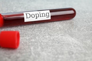 Photo of Tube of blood with word Doping on light grey stone table, closeup. Space for text