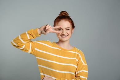 Portrait of cheerful red haired woman on grey background