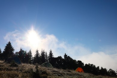 Picturesque mountain landscape with camping tents in morning. Space for text
