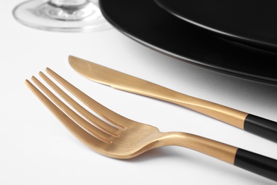 Beautiful setting with gold cutlery on white table, closeup