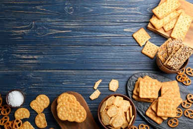Many delicious crackers on blue wooden table, flat lay. Space for text
