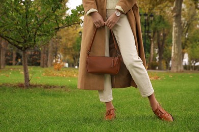 Stylish woman with trendy leather bag in autumn park, closeup