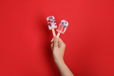 Woman holding berry popsicles on red background, closeup