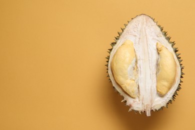 Photo of Half of fresh ripe durian on orange background, top view. Space for text