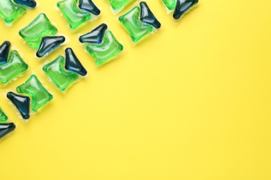 Laundry capsules on yellow background, flat lay. Space for text